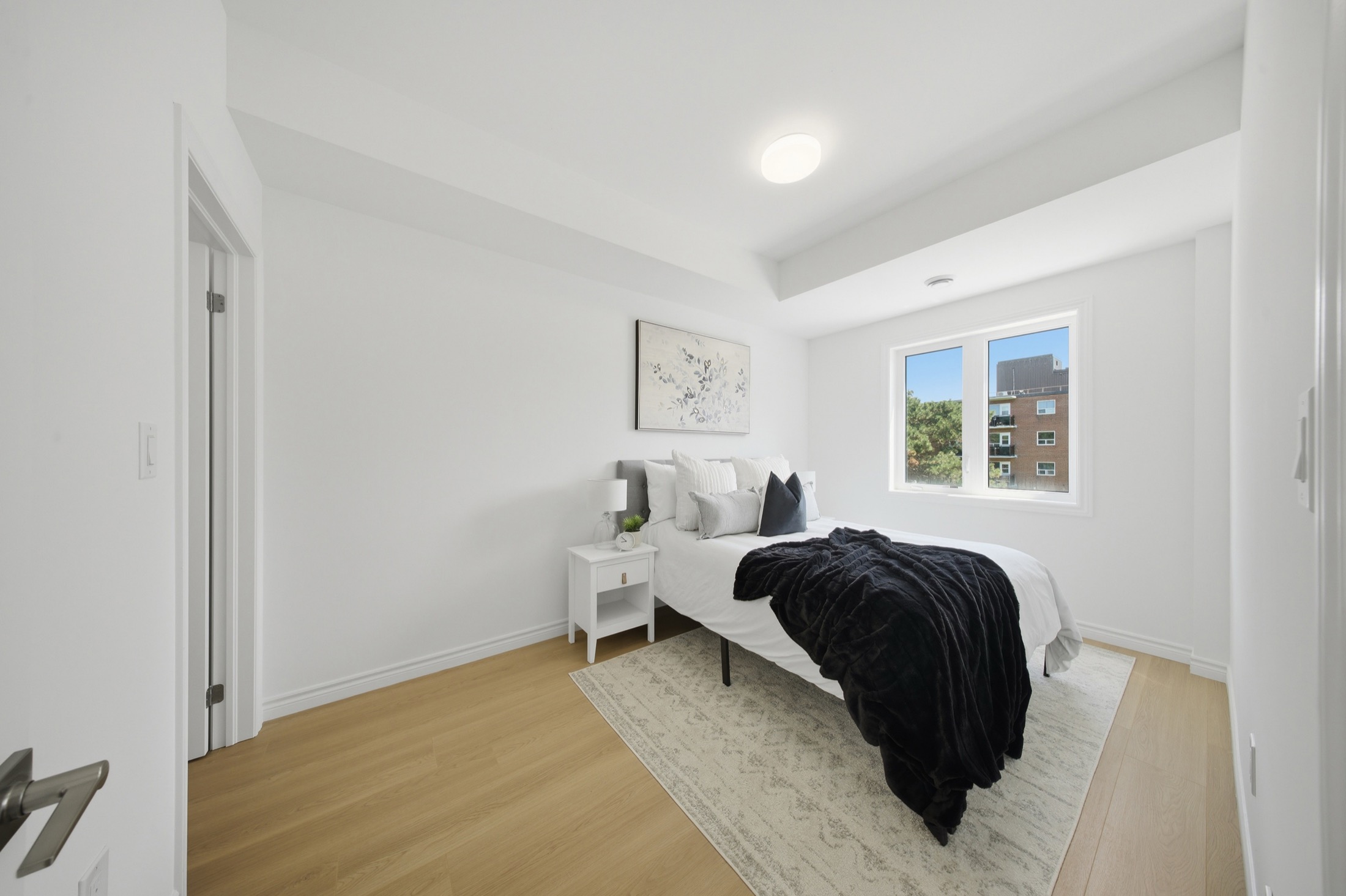 Second bedroom with wide-plank oak flooring and a bright window