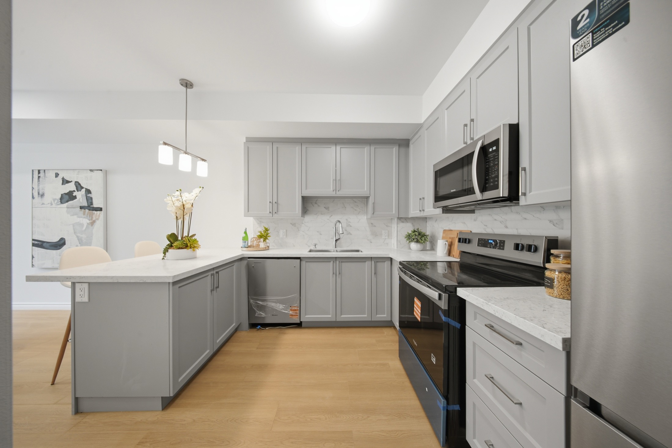Kitchen with grey shaker cabinetry, quartz counters and stainless appliances